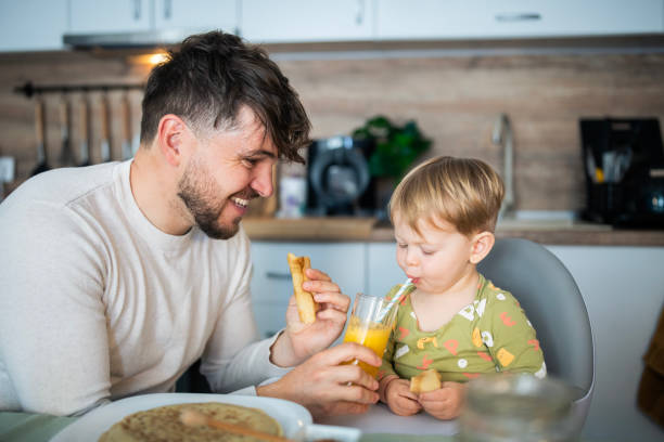 istock Happy father sharing breakfast with his little son at the kitchen table. 2103861858