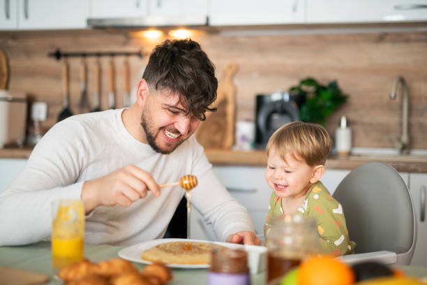 istock Happy father sharing breakfast with his little son at the kitchen table. 2103862282
