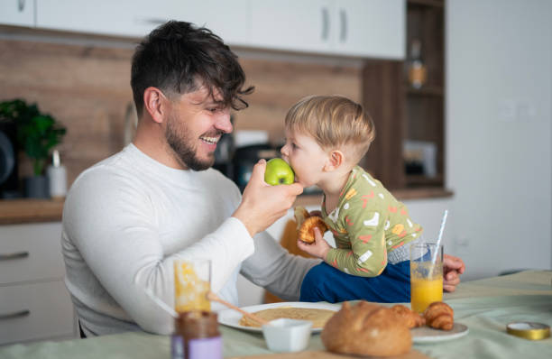 istock Father and toddler son having breakfast at kitchen table. 2103862812