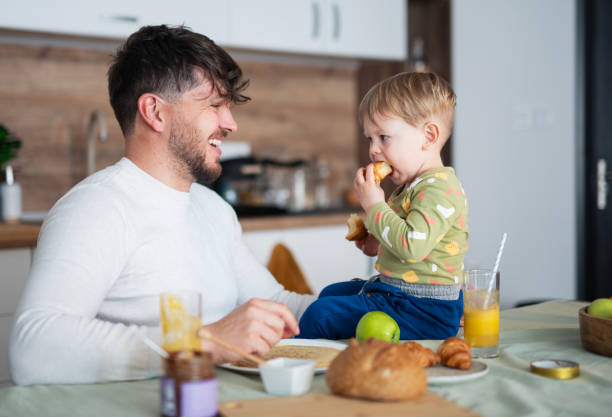istock Father and toddler son having breakfast at kitchen table. 2103862819