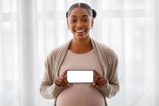 istock Happy pregnant black lady holding horizontal blank cellphone 2103864903