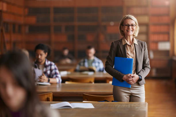 istock Happy mature professor with her student in library. 2103871364