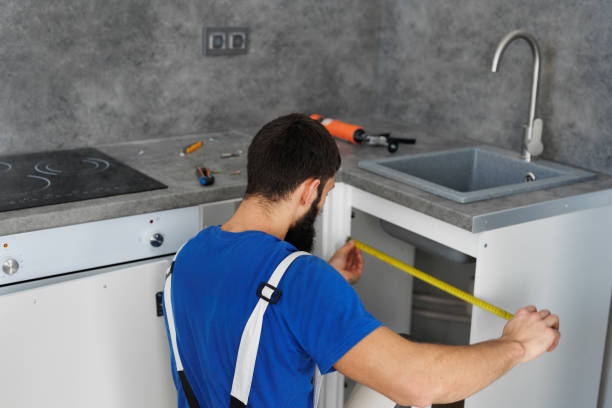 istock A furniture assembler or builder uses a tape measure to install cabinets for a new kitchen. 2103872978