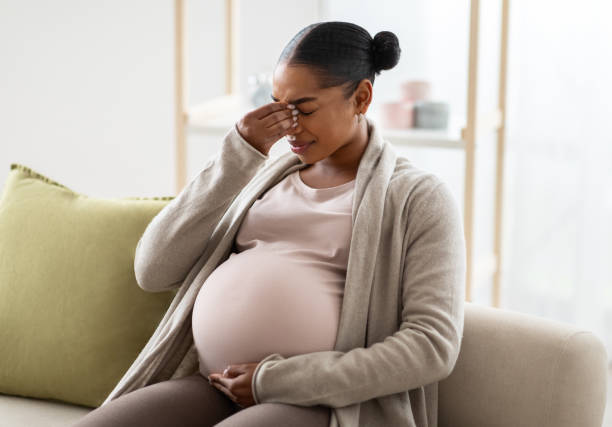 Young pregnant black woman suffering from headache or migraine ストックフォト