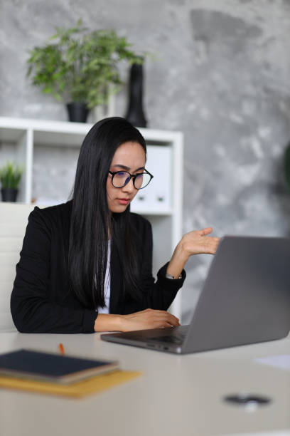 istock A professional asian woman sits confidently at her workplace, using her laptop for successful business endeavors. 2103895069