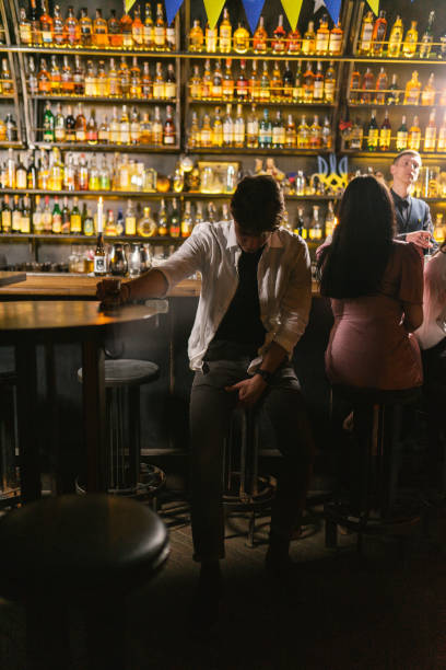 istock Tired drunk man with shot glass sits at round table in bar 2103895584