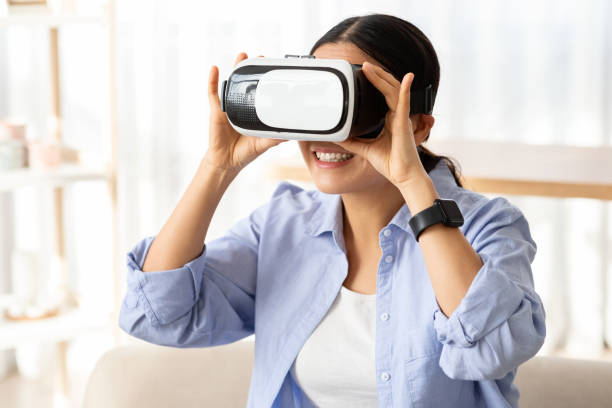 istock Asian lady in virtual reality headset exploring cyberspace indoors 2103896146