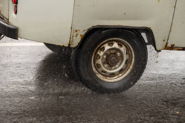 old rusty soviet minivan driving on the wet asphalt road during heavy rain - skidding car tire rain stock-fotos und bilder