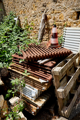 Rusty, Used Radiators Stacked Against Stone Wall