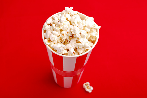 Popcorn in red and white cardboard box. Popcorn border isolated on white. Film. Fast food. Corn