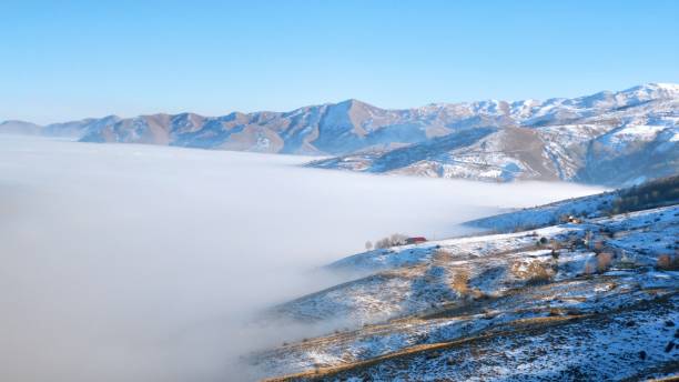 wiejski dom na skraju pokrytej mgłą doliny wśród ośnieżonych gór - street fog profile zdjęcia i obrazy z banku zdjęć