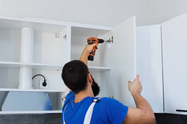 istock A man in uniform screws the kitchen cabinet doors with an electric screwdriver. 2103909340