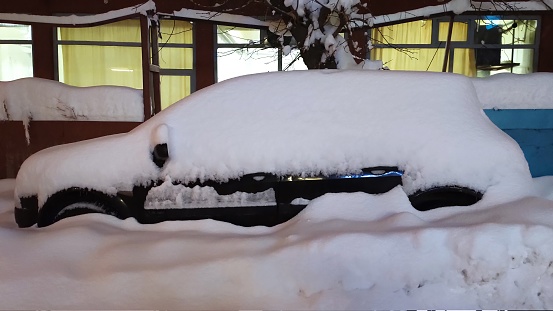 A parked black car covered in snow