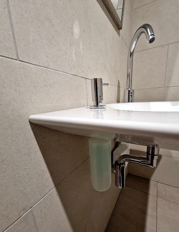 pump soap dispenser for liquid soap. the container is screw-on and the container is directly under the sink. hand washing via a stainless steel dispenser with a pump button