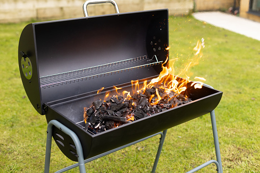 Empty flaming charcoal grill with open fire, ready for product placement. Concept of summer grilling, barbecue, bbq and party. Black copyspace