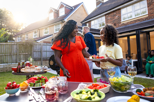 A three-quarter length shot of a mid-adult female laughing with her daughter. They are all wearing casual clothing and enjoying freshly prepared food. The house is located in Newcastle Upon Tyne, England.\n\nVideos are available similar to this scenario