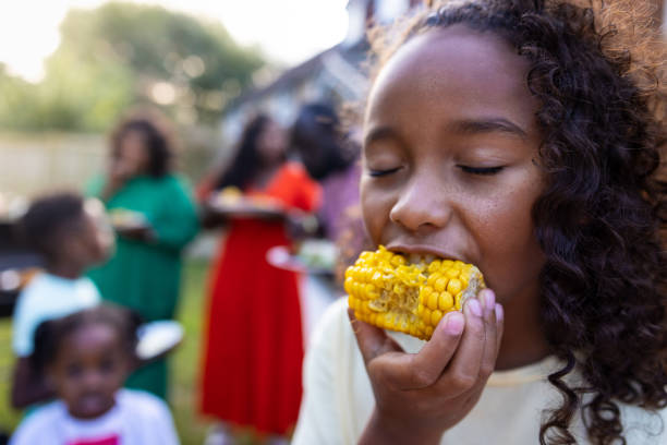 istock Mixed Race Girl Eating Corn on The Cob 2103933011