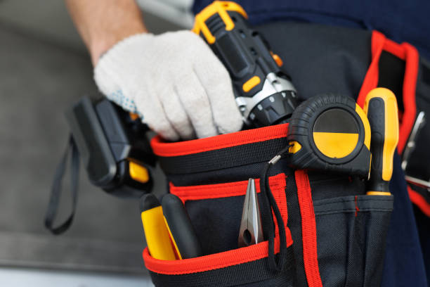 istock A handyman with a tool belt and craft equipment holds a drill in his hand. 2103940663