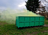 a container with chemical toxic waste from which green smoke comes out. radioactive waste in a bio-waste container. one of the drivers is bothering you with the smell. composting, military smokestack, neighborhood