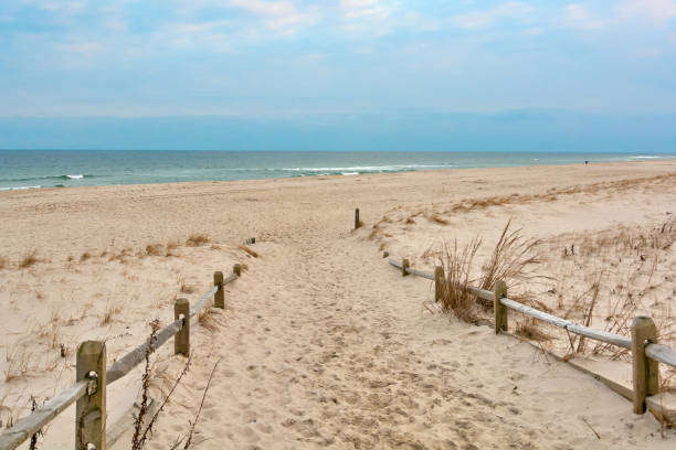 istock Boardwalk towards calm surrounded by sand on the beach 2103952153