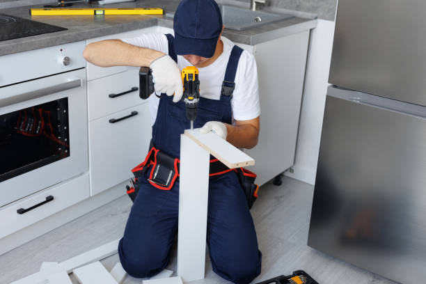 istock Master in uniform is assembling new furniture in the kitchen with a screwdriver. 2103980636