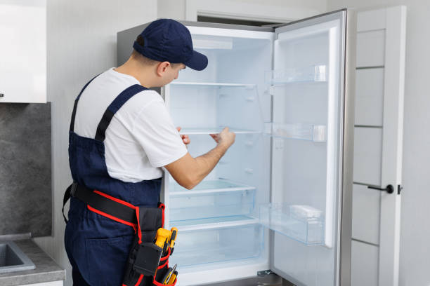 istock Man in a uniform with tools is repairing a refrigerator in the kitchen. 2103986886
