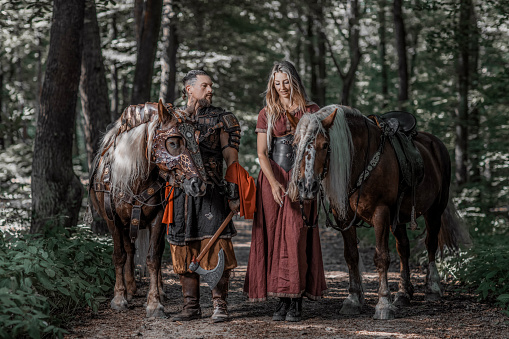 A loving male and female viking couple in an woodland outdoor setting with horses