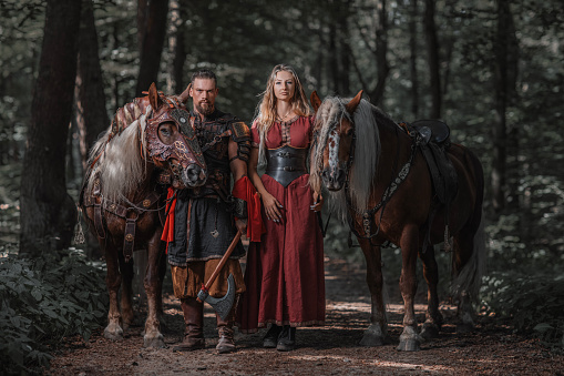 A loving male and female viking couple in an woodland outdoor setting with horses