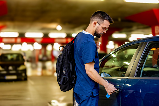 Healthcare worker holding car keys next to automobile, after work