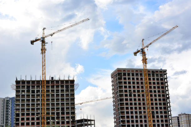 two cranes are in front of a building with a sky on background
