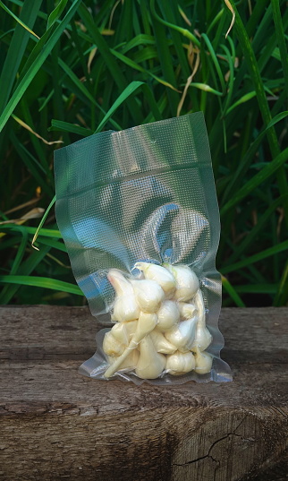 Garlic in a vacuum bag. Greenery Background. Harvest time