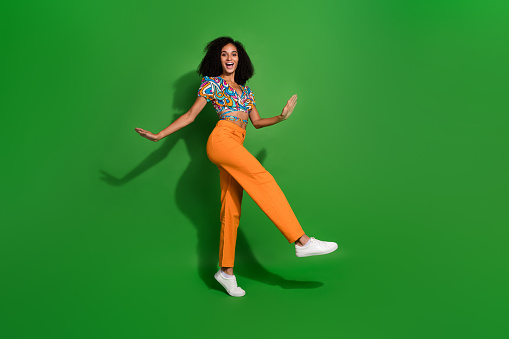 Full body length photo of young girl wearing festive retro style top and pants dancing boogie woogie isolated on green color background.