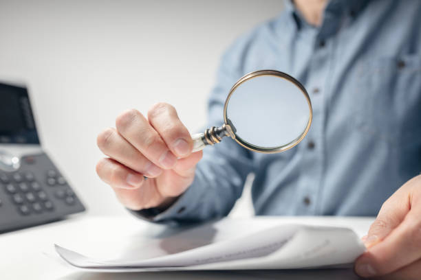 istock Man with magnifying glass reading documents or legal contract 2104018698