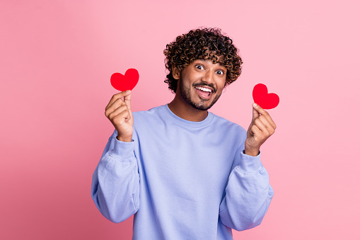 Photo of positive glad man wear stylish blue clothes hold red postcards valentine day party isolated on pink color background.