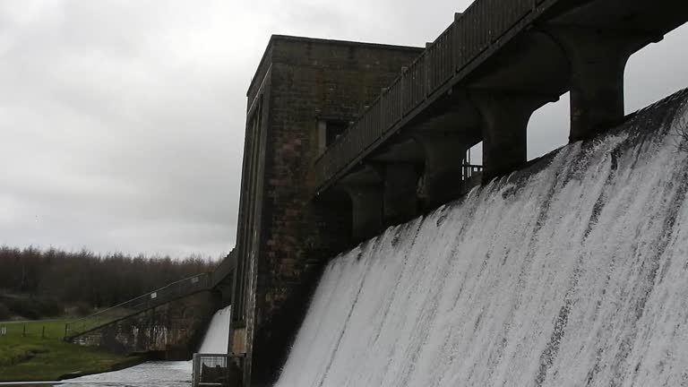 Llyn Cefni reservoir concrete dam gate pouring from Llangefni lagoon, Anglesey rural scene close up