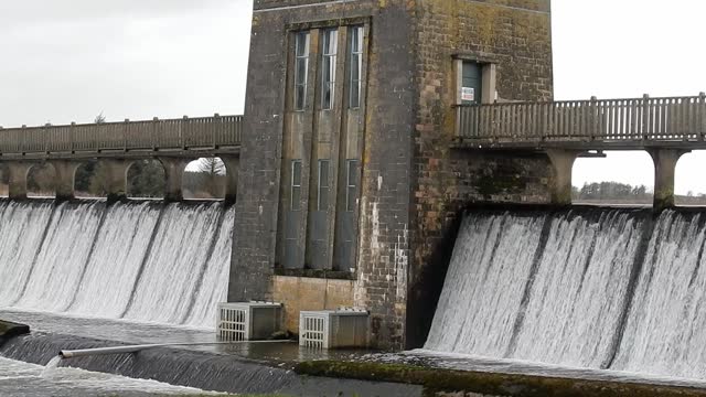 Llyn Cefni reservoir concrete generator gate overflowing from Llangefni lagoon in Anglesey, North Wales