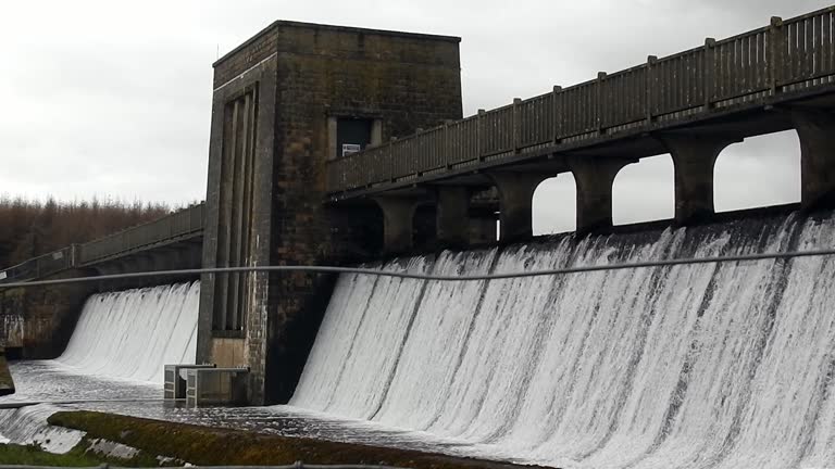 Llyn Cefni reservoir concrete dam gate pouring from Llangefni lagoon, Anglesey rural scene