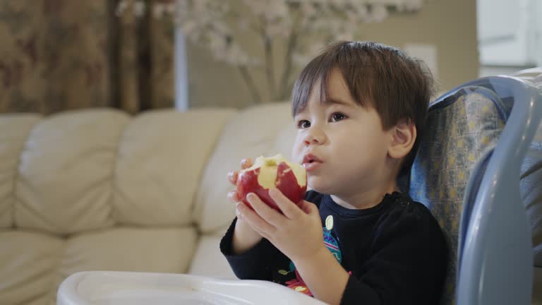 Two-year-old kid eats a big red apple