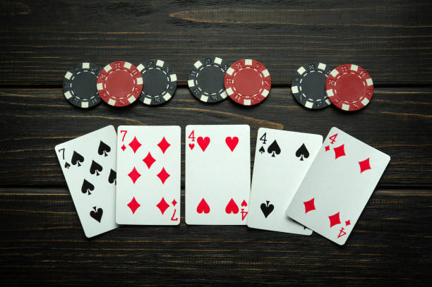 istock Chaotically lying playing cards and chips on a vintage dark table in a casino. Low key concept of a successful combination of a full house or full boat in a poker club 2104102947