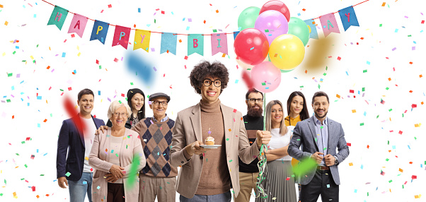 Young man with a birthday cupcake and a bunch of balloons celebrating with people isolated on white background