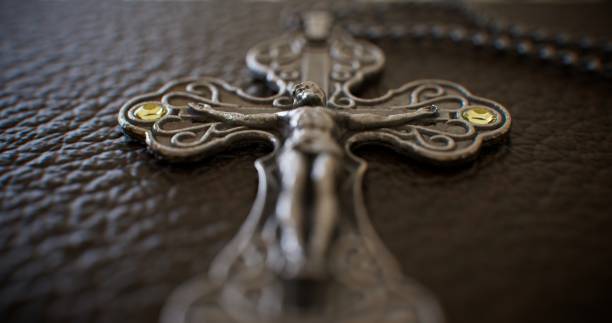 Adorned with opulence, the soft leather cover of a luxurious Bible showcases a breathtaking silver cross, its intricate design catching the light and casting a celestial radiance