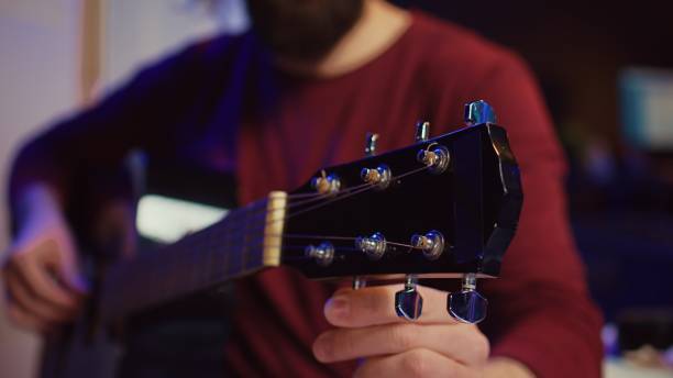 istock Musical performer tuning his guitar by twisting the knobs 2104134826