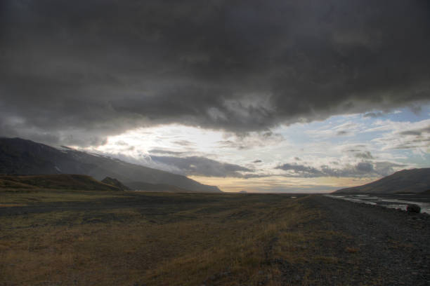 the heavy clouds at sunset settle over a vast plain in iceland - mountain alpenglow glowing lake foto e immagini stock