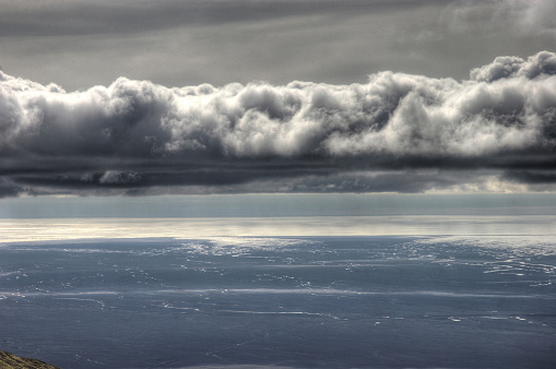 Heavy clouds sit above the ocean and lava flats on the edge of Iceland's south coast