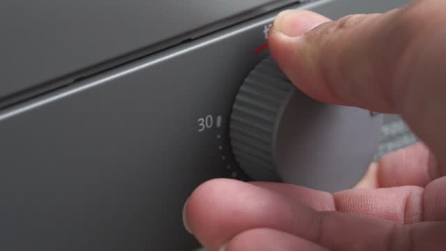 Man's hand turning the dial of a toaster oven