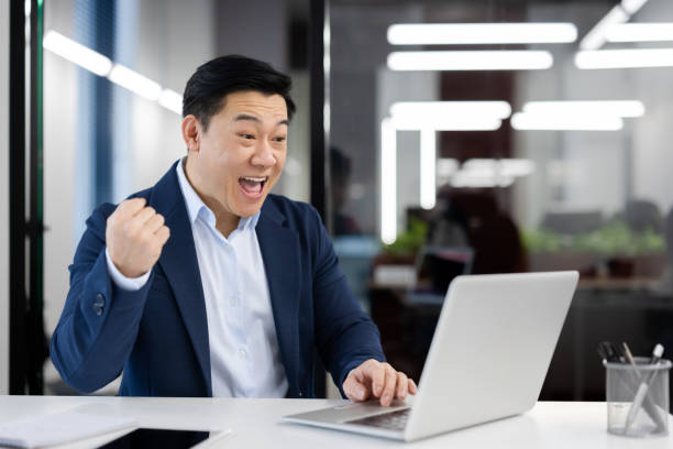 istock Successful asian businessman celebrating victory at work in modern office 2104153201