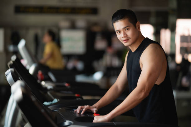 istock Asian athlete sport man runner touch start buttom before workout running on treadmill in fitness club. Cardio workout. Healthy lifestyle, guy training in gym. Sport running concept 2104159603