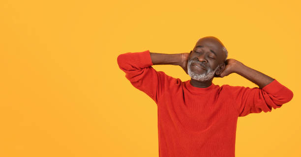 istock Relaxed and content senior man in a red sweater, with hands behind his head 2104160743