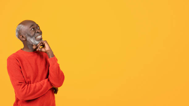 istock Pensive cheerful senior black man in red sweater look at free space, dream, think 2104161313