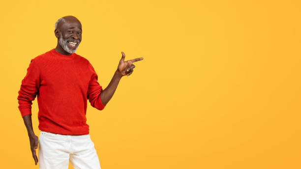 istock Confident senior Black man with a white beard, pointing to his right with a friendly smile 2104161336